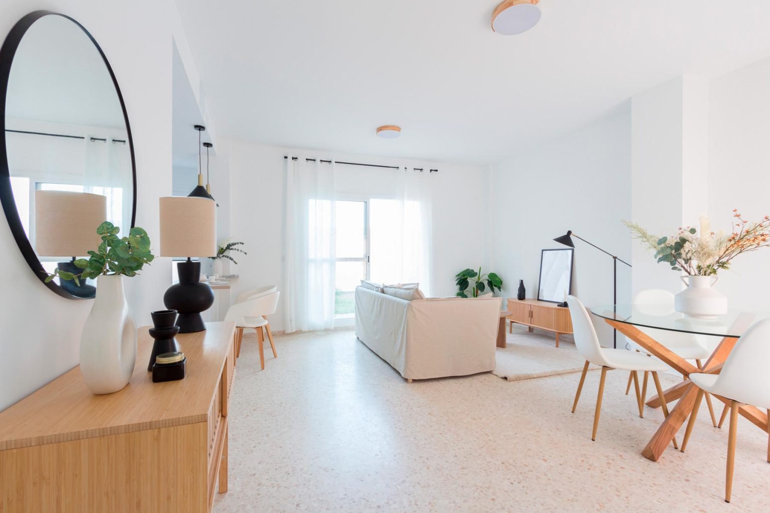 Pisos en alquiler de larga duración con Home staging de salón comedor luminoso para alquiler de larga duración, con sofá blanco, mobiliario de madera, tonos neutros y decoración moderna | Realzo