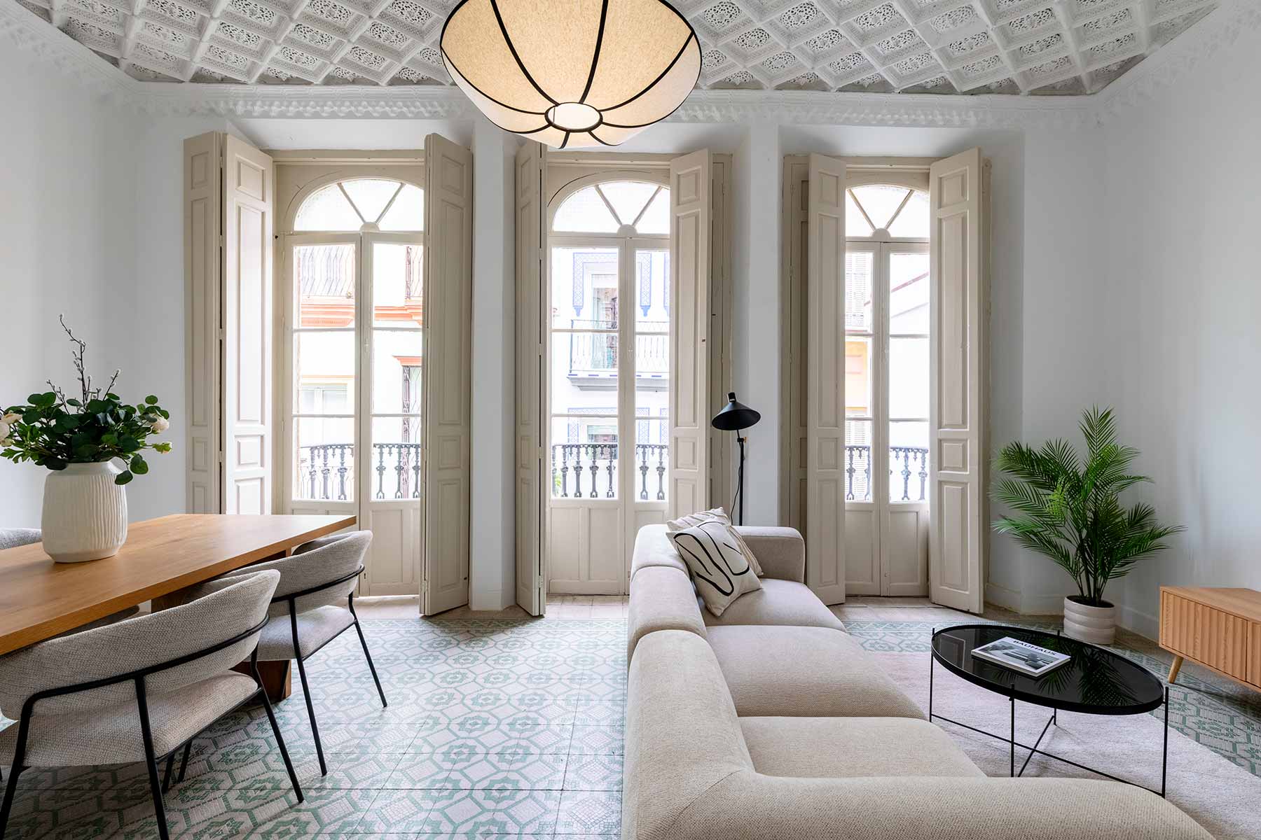 Interiorismo de salón comedor en vivienda rehabilitada con techos ornamentales, ventanales clásicos, suelo hidráulico y mobiliario contemporáneo | Realzo